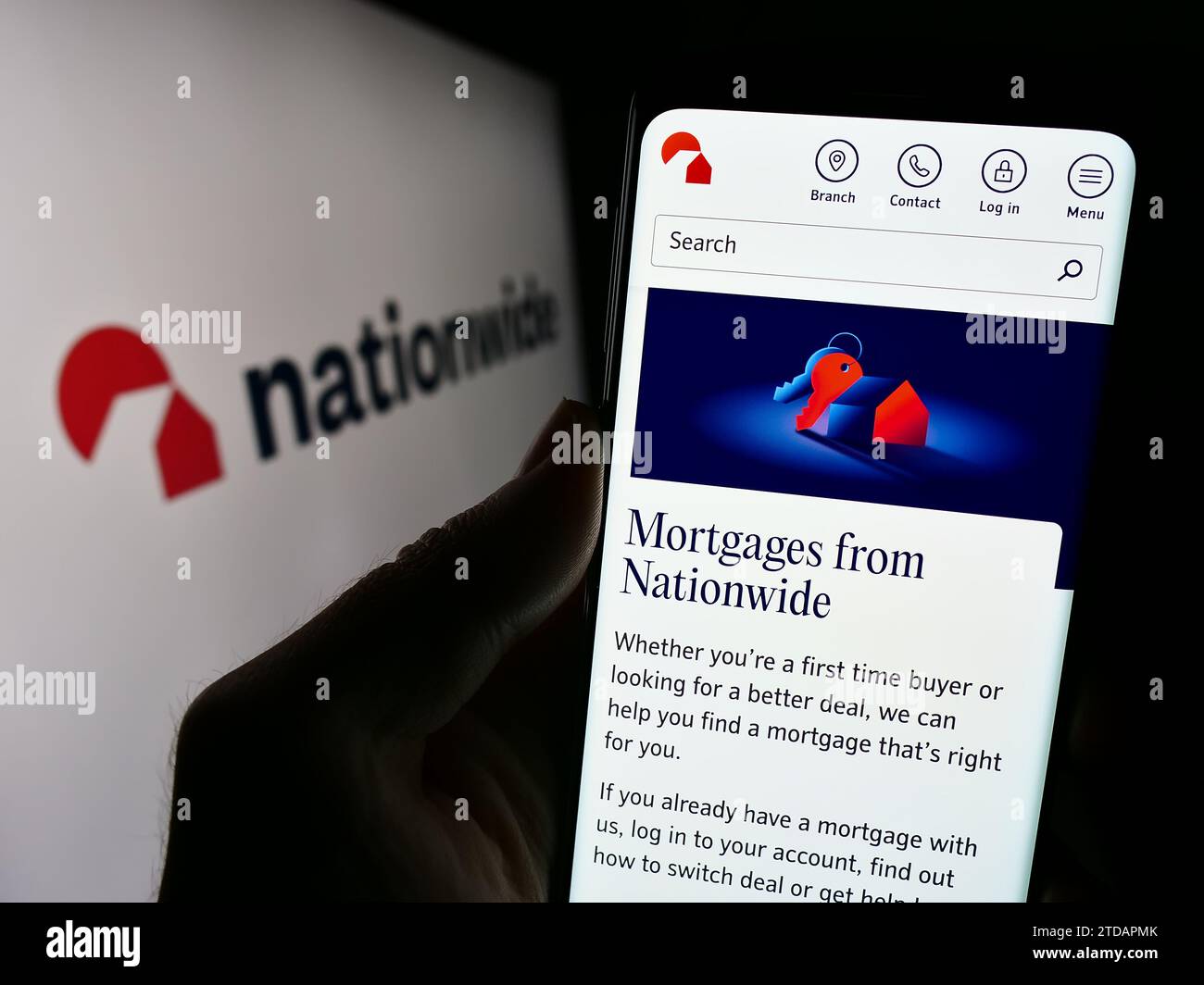 Person holding cellphone with webpage of British financial institution Nationwide Building Society with logo. Focus on center of phone display. Stock Photo