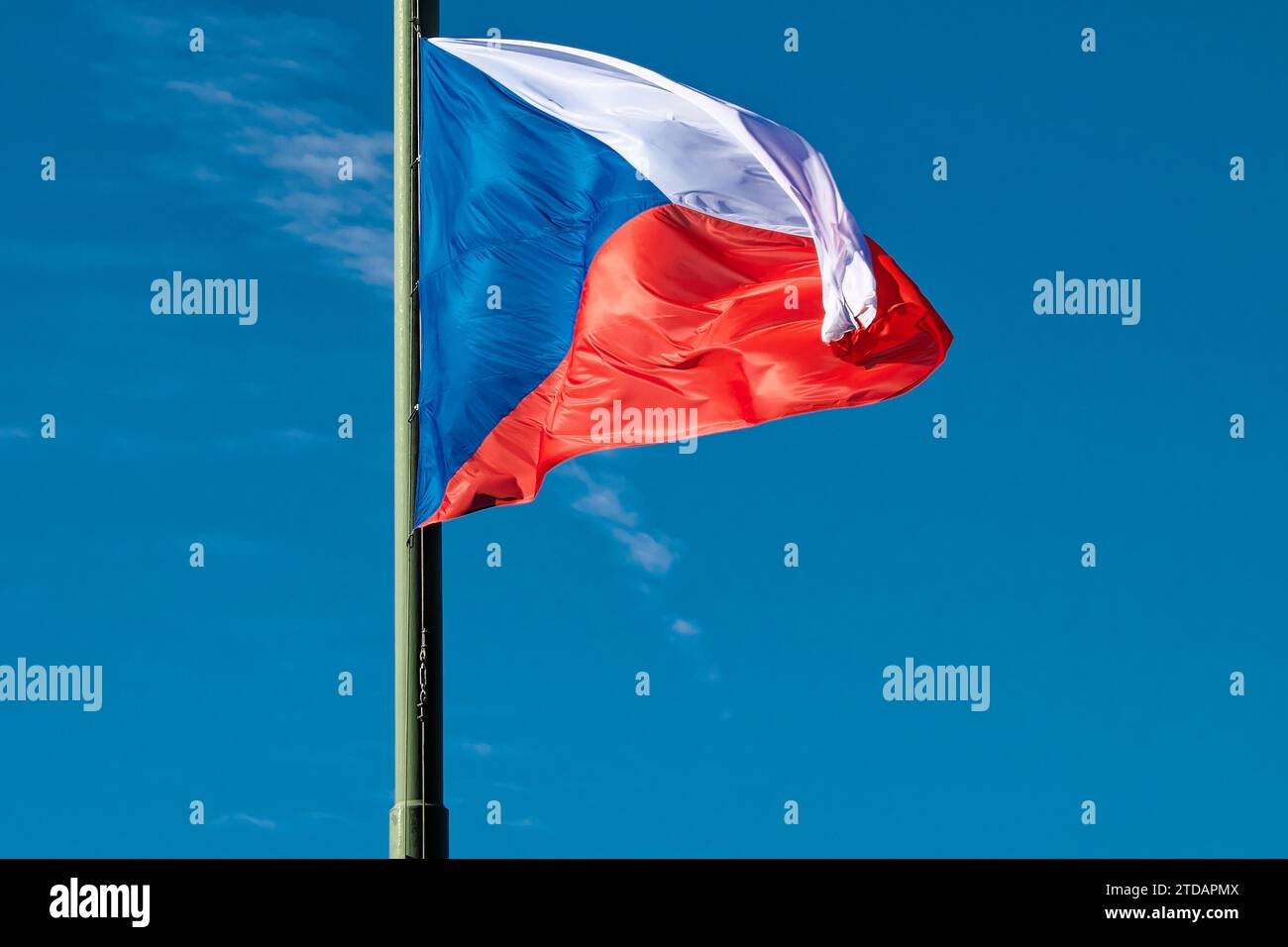 A photo of the Czech Republic flag flying on a flagpole with a blue sky in the background. Stock Photo
