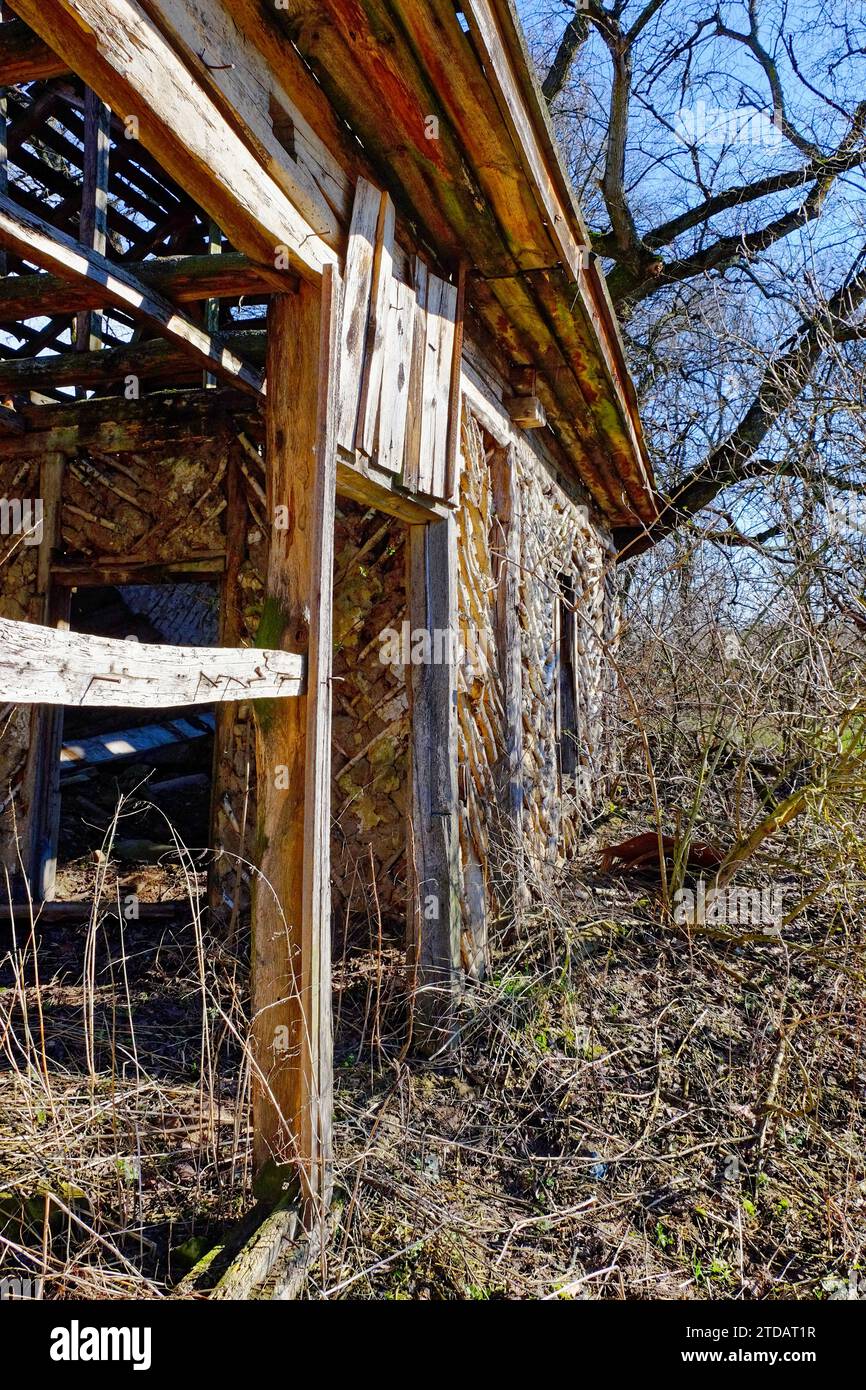 The image shows an abandoned wooden house with a collapsed roof ...