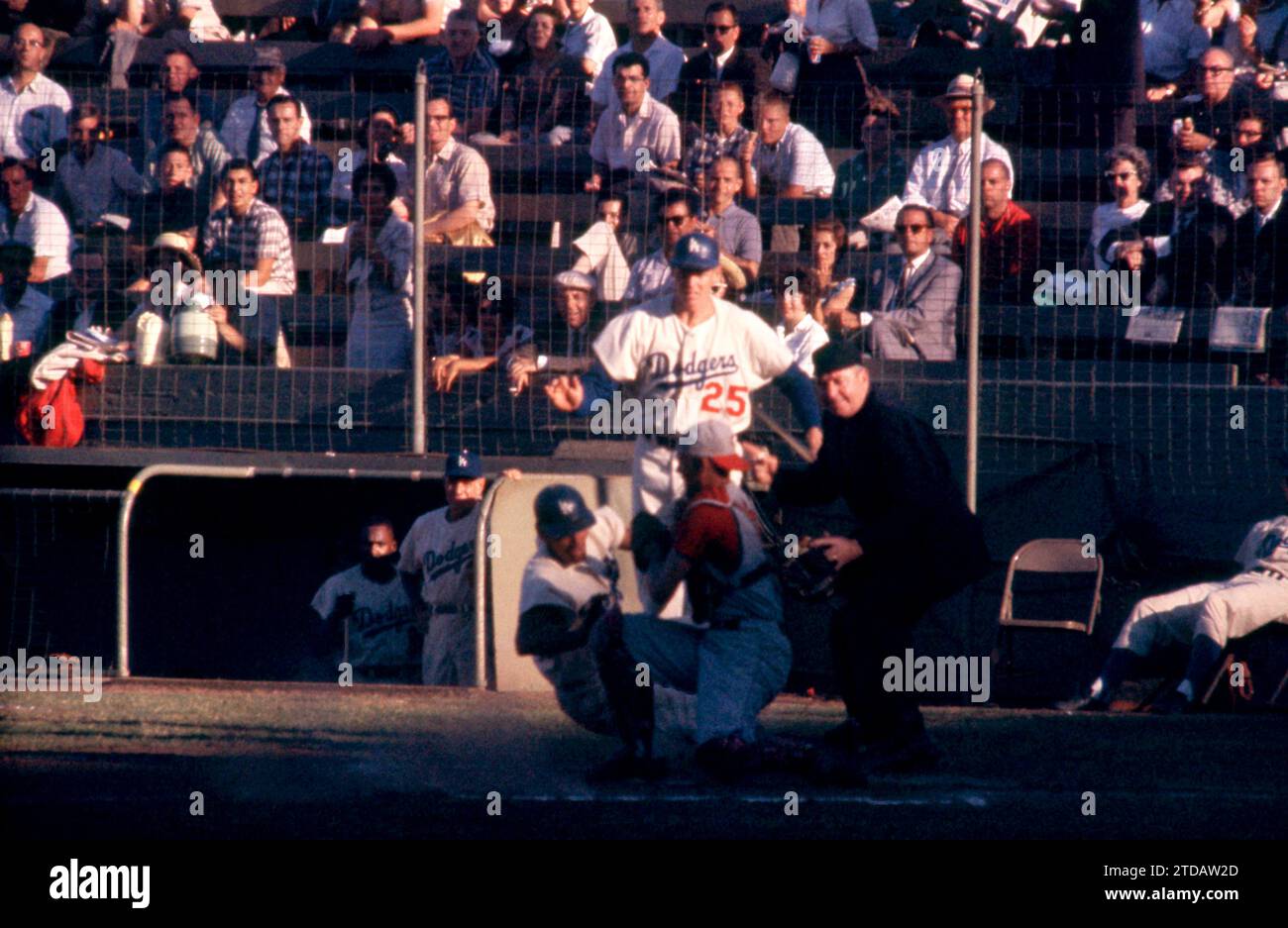 LOS ANGELES, CA - JULY 7:  Wally Moon #9 of the Los Angeles Dodgers slides safely under the tag from catcher Jerry Zimmerman #8 of the Cincinnati Reds as home plate umpire Tom Gorman is there to make the call as Frank Howard #25 of the Dodgers looks on during the first game of the doubleheader on July 7, 1961 at the Los Angeles Memorial Coliseum in Los Angeles, California.  (Photo by Hy Peskin) *** Local Caption *** Frank Howard;Wally Moon;Jerry Zimmerman;Tom Gorman Stock Photo