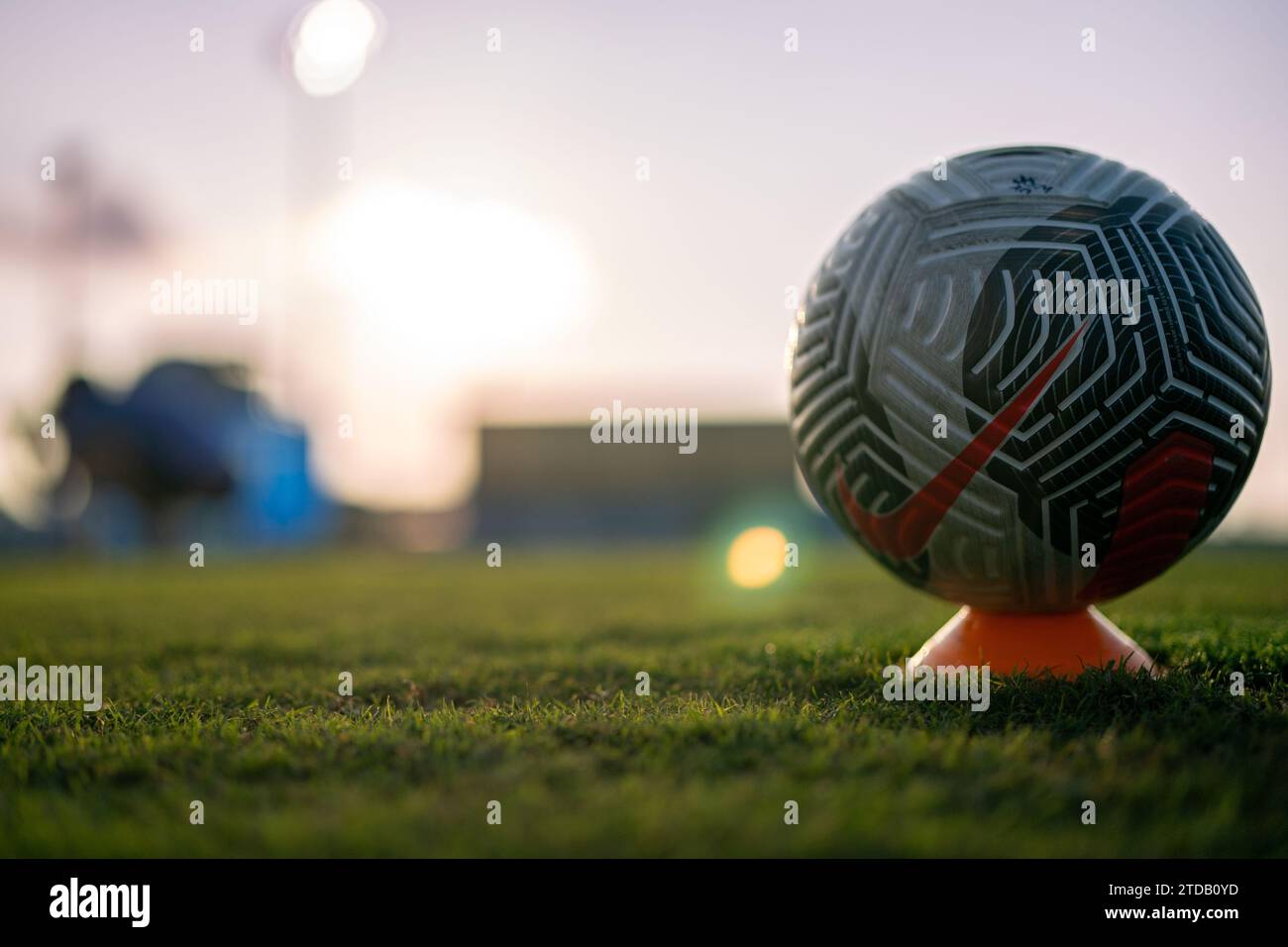 A soccer ball rest on the pitch before a match while players are running pre match warmups Stock Photo