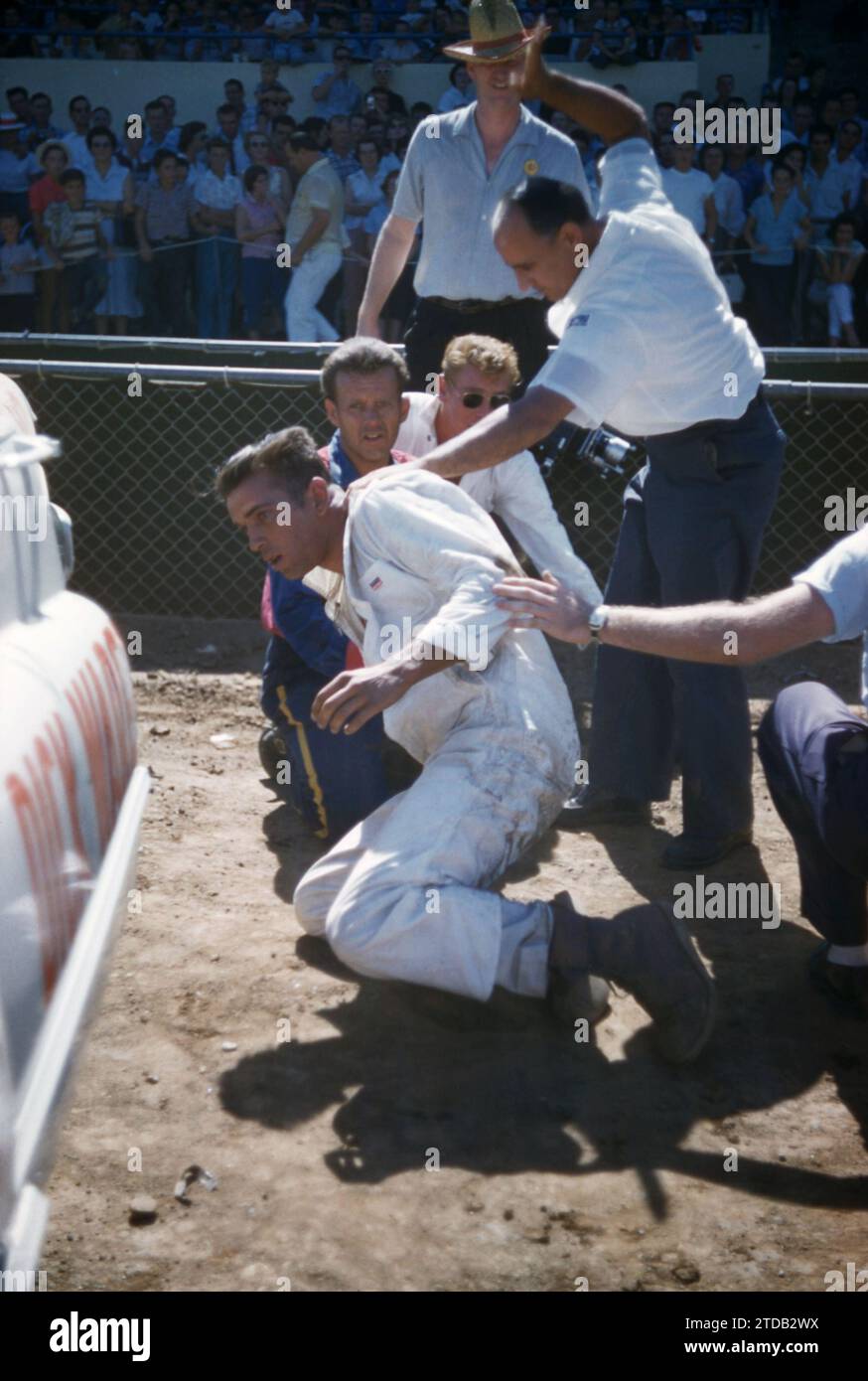 SACRAMENTO, CA - AUGUST, 1958: A group of men tend to the driver after his car flipped and crashed during a car show at the Sacramento State Fair circa August, 1958 in Sacramento, California. (Photo by Hy Peskin) Stock Photo