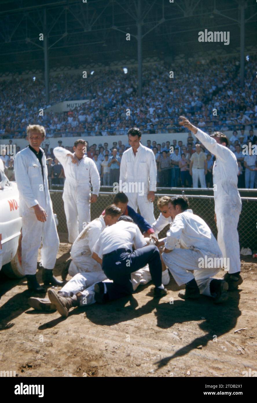 SACRAMENTO, CA - AUGUST, 1958: A group of men tend to the driver after his car flipped and crashed during a car show at the Sacramento State Fair circa August, 1958 in Sacramento, California. (Photo by Hy Peskin) Stock Photo