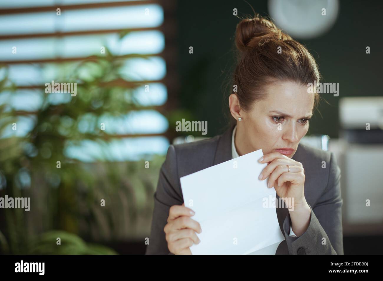 New job. pensive modern female employee in modern green office in grey ...
