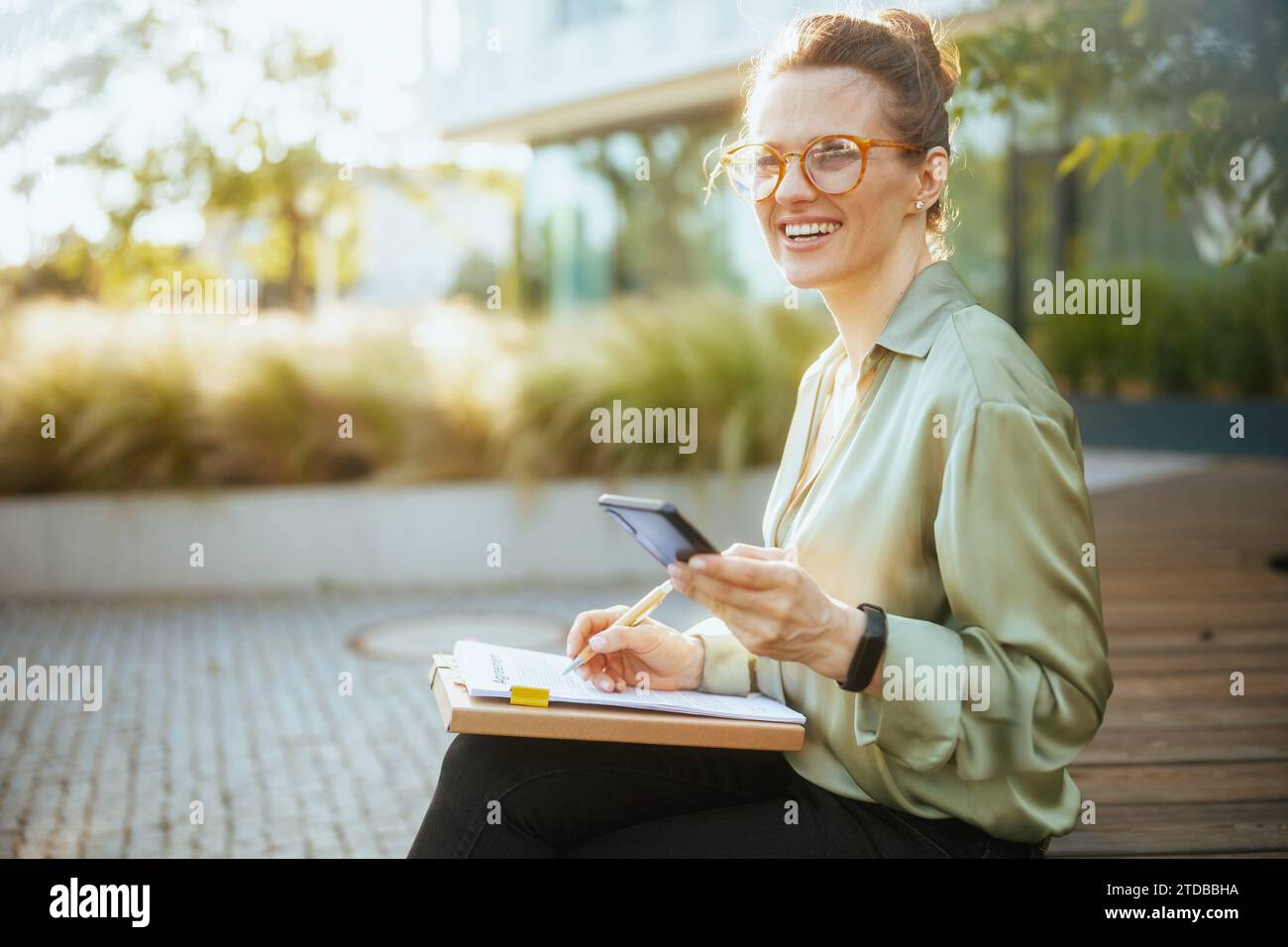 smiling modern female worker in business district in green blouse and ...