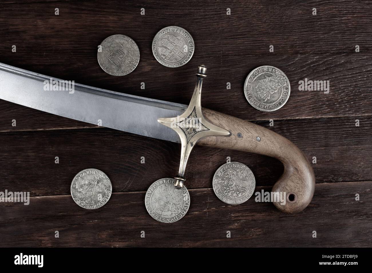 Ukraine Saber Sword with silver taller coins on wooden deck, 17th century. Poland, Lithuania, Hungary, Ukraine. Stock Photo