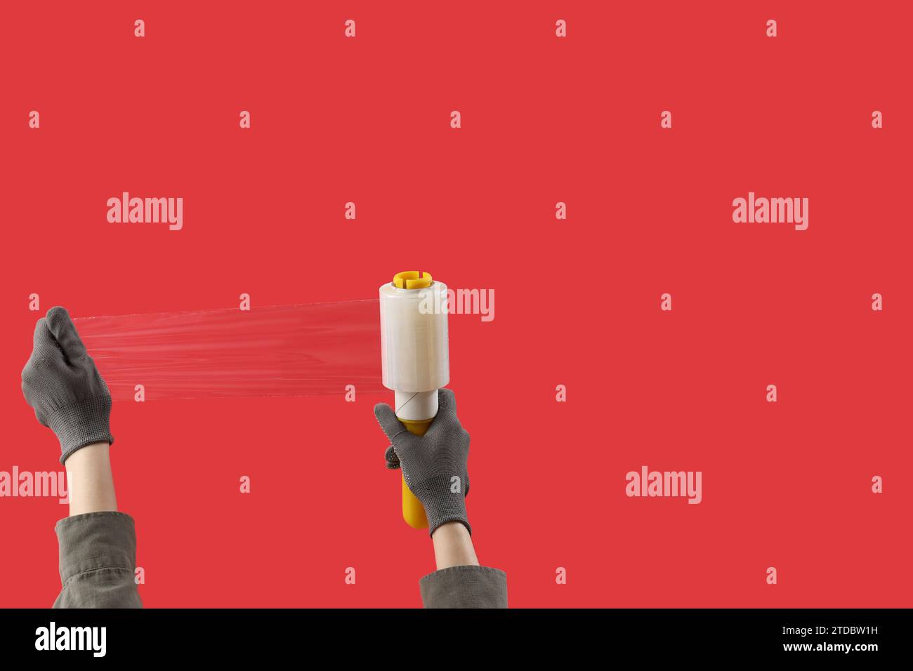 Female hands in gloves holding stretch film dispenser on red background