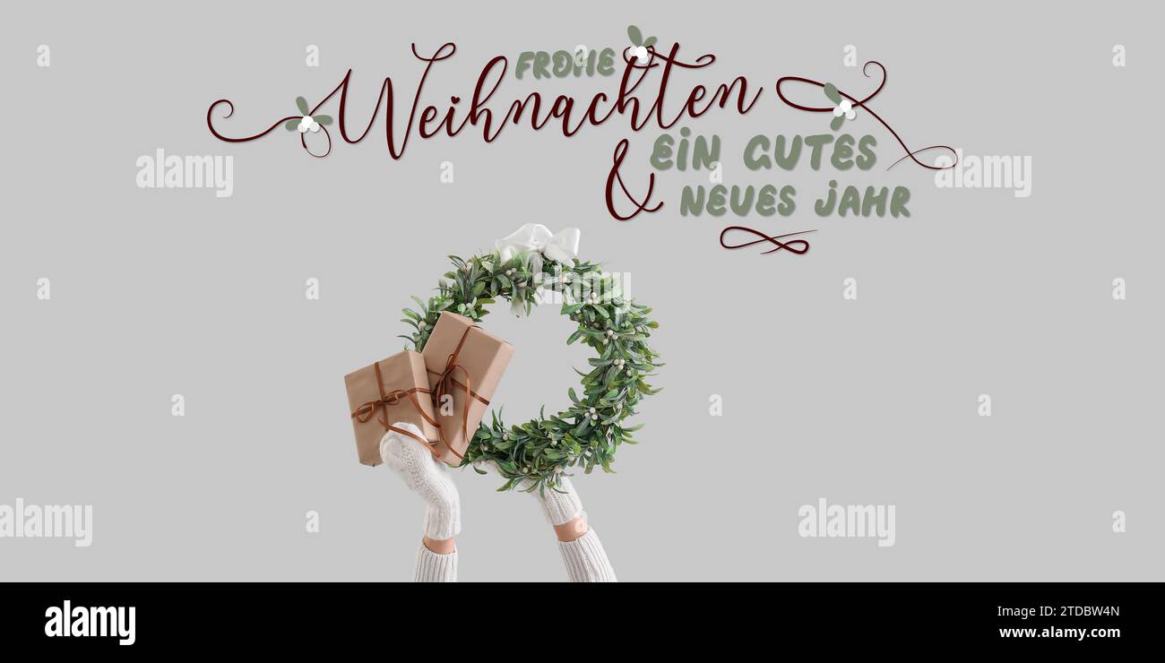 Text FROHE WEIHNACHTEN END GUTES NEUES JAHR (German for Merry Christmas and Happy New Year) and hands with mistletoe wreath and gifts on light backgro Stock Photo