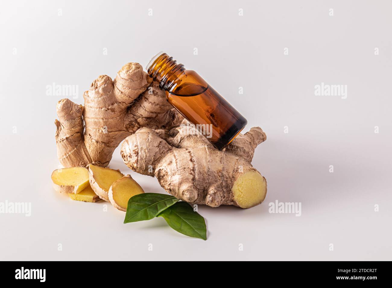 An amber glass bottle with a dropper with a natural remedy or ginger oil lies on the ginger root. Skin rejuvenation, hair strengthening, spa Stock Photo