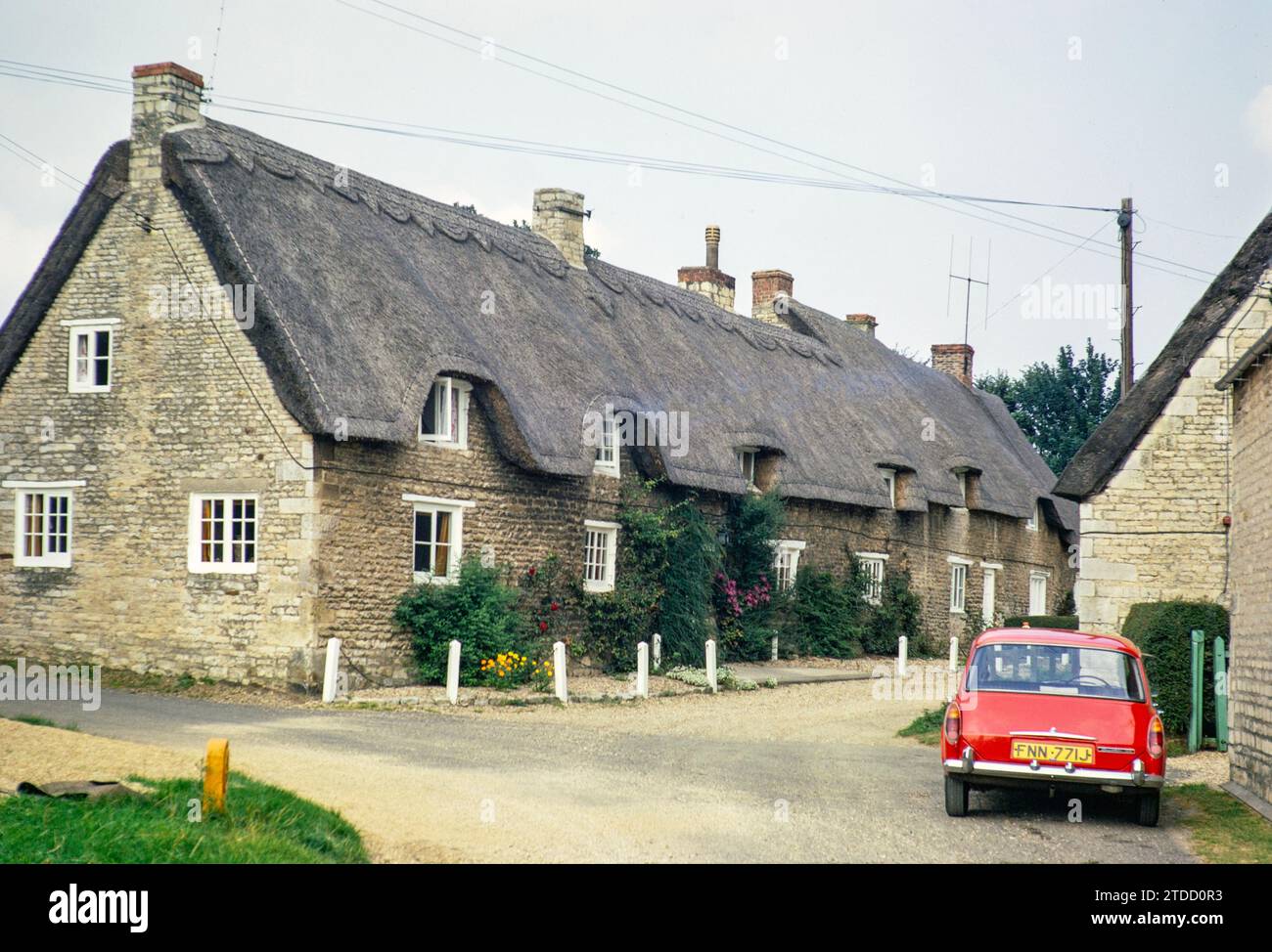 Thatched cottages in Crocket Lane,  village of Empingham, Rutland, England, UK August 1972 Red Austin Morris 1100 Mk 2 car Stock Photo