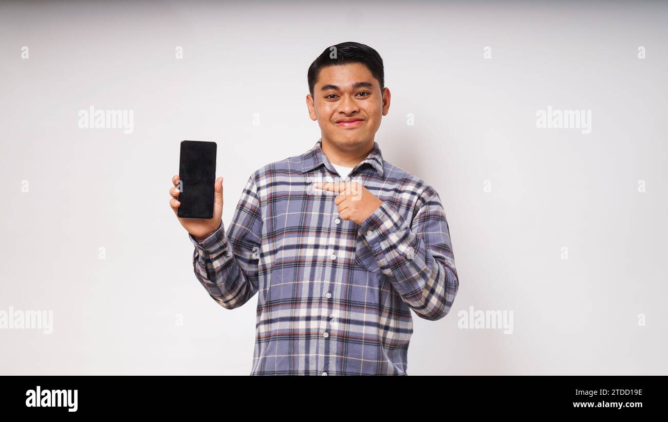Smiling happy Young Asian man showing blank phone screen with excited expression on white background. studio shot Stock Photo