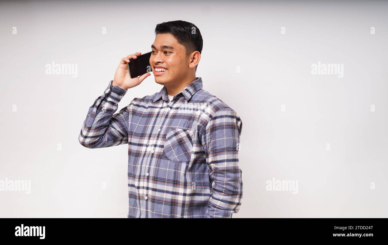 Asian young man showing happy face expression while talking on smartphone. studio shots against white background Stock Photo
