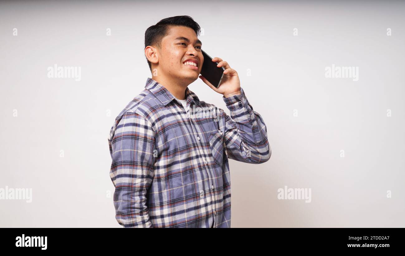 Asian young man showing happy face expression while talking on smartphone. studio shots against white background Stock Photo