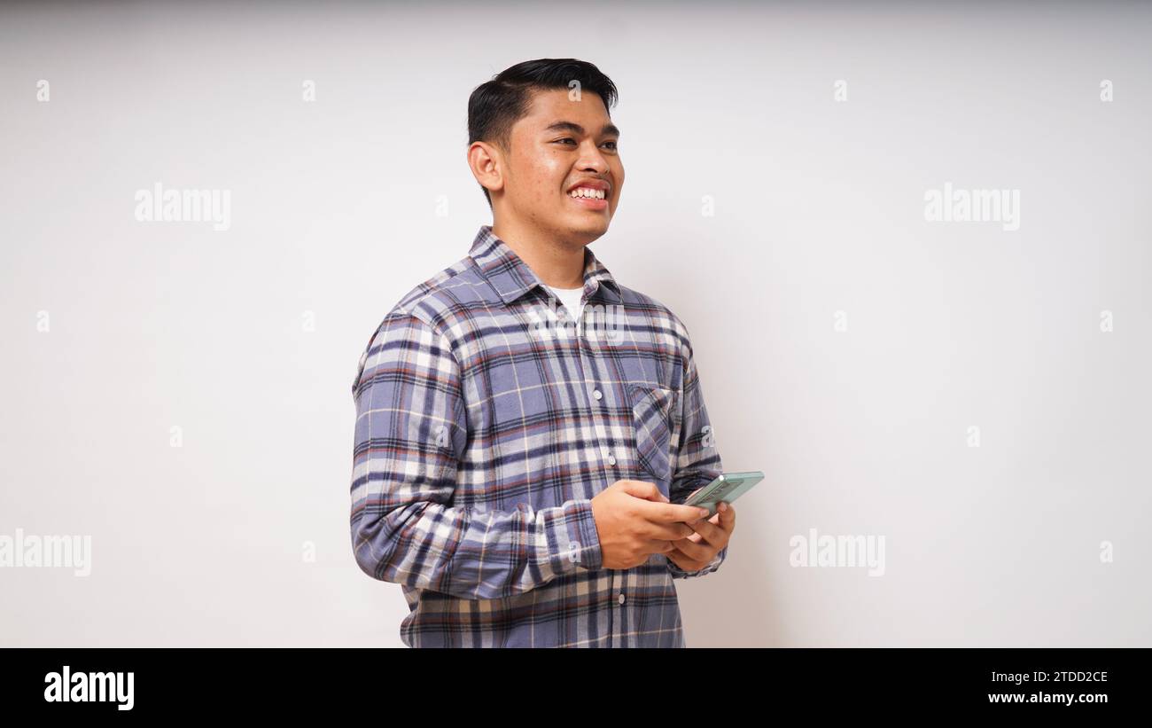 Young Asian man holding mobile phone showing enthusiastic expression Stock Photo