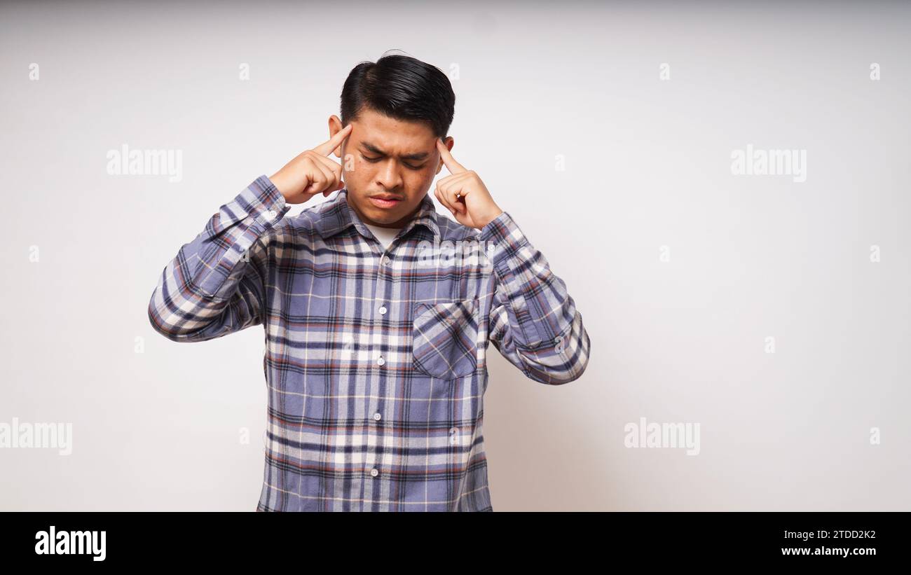 Asian young man showing in pain expression while touching his head Stock Photo