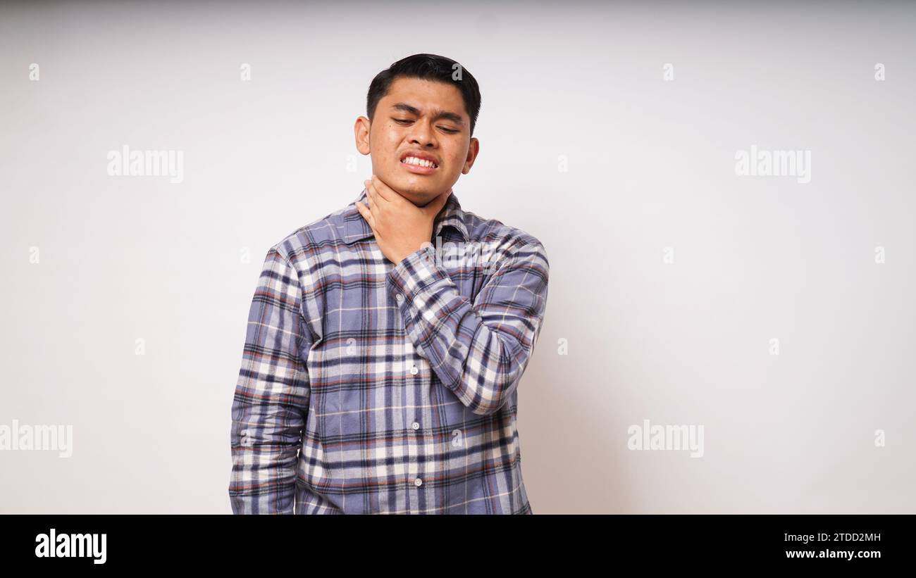 Young Asian man touching his throat showing in pain expression on white background. studio shot Stock Photo