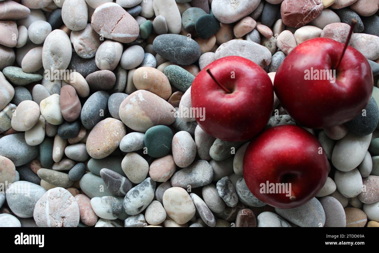 Three red ripe apple fruits on a sea stones at a side of image concept for logo or titles Stock Photo