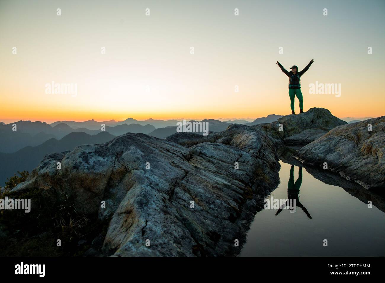 Reflection of strong fit woman trail runner on mountain summit Stock Photo