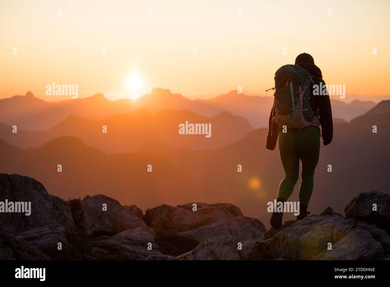 Rear view of female backpacker hiking on mountain summit. Stock Photo