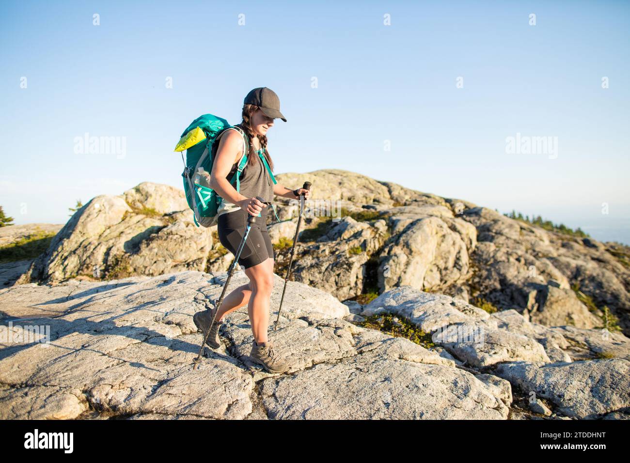 Side view of athletic woman backpacker on mountain summit Stock Photo