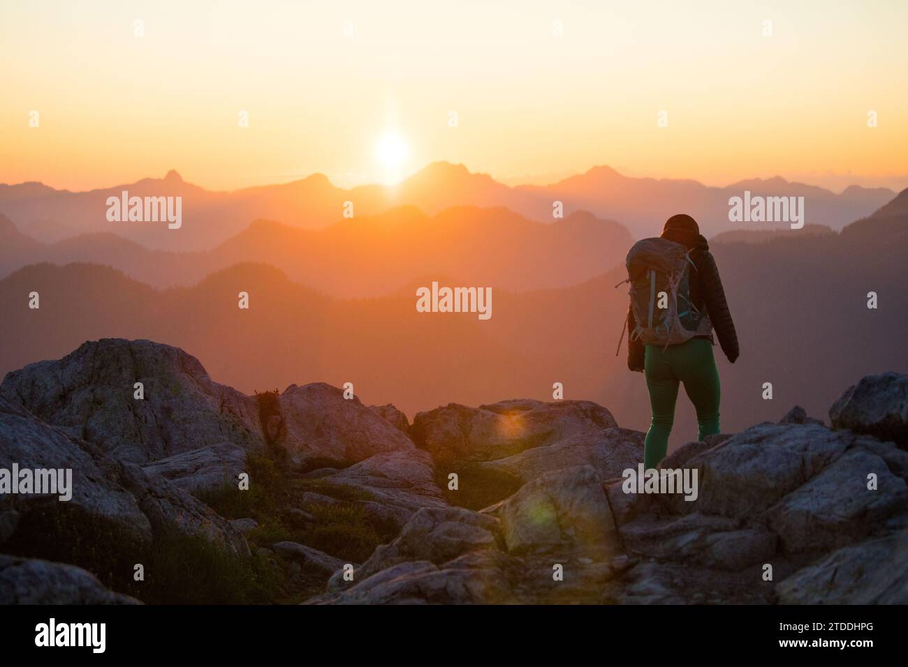 Backpacker hiking on mountain summit, scenic view at sunset Stock Photo