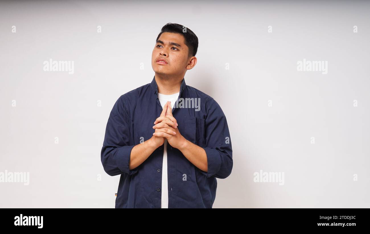 Young Asian man showing thinking gesture with his eyes looking up on white background. studio shot Stock Photo