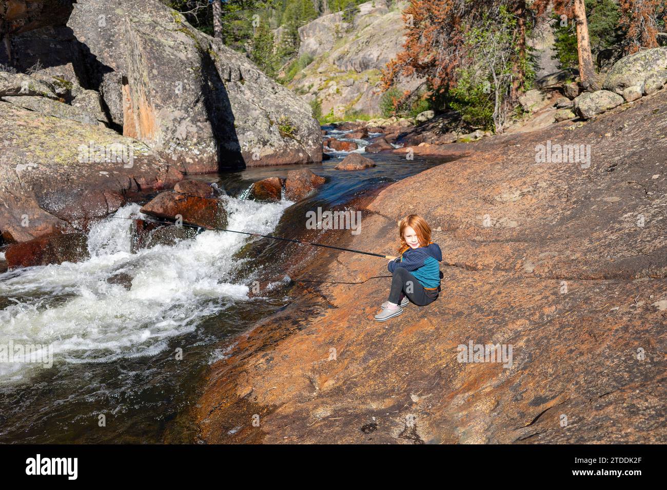 Child fishing in a waterhole near a waterfall, Colorado Stock Photo