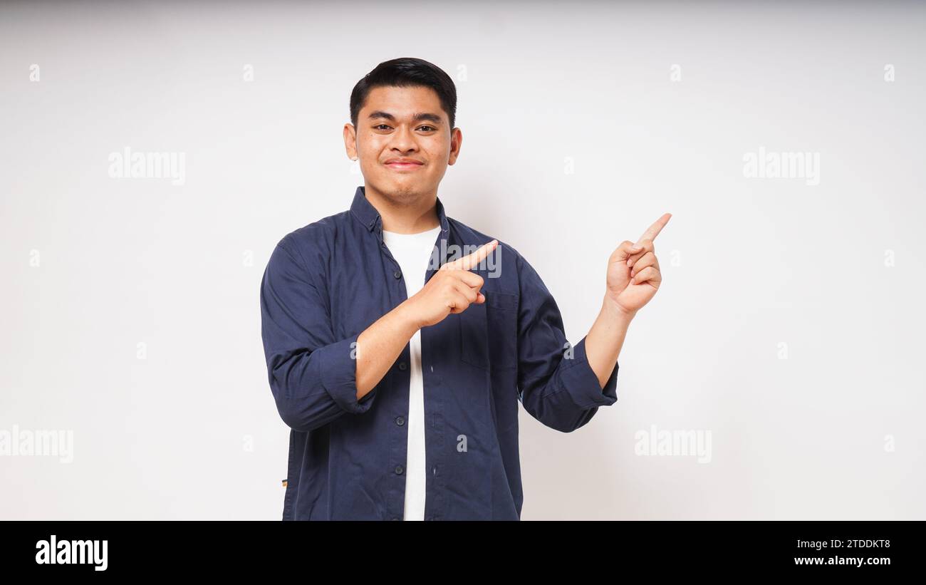 Young Asian man smiling when looking and pointing to the left side on white background. studio shot Stock Photo