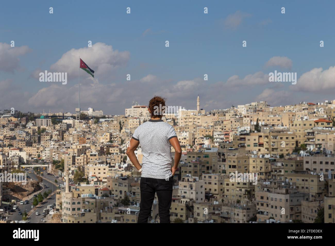 Male tourist looking at Amman's cityscape during sunny day Stock Photo