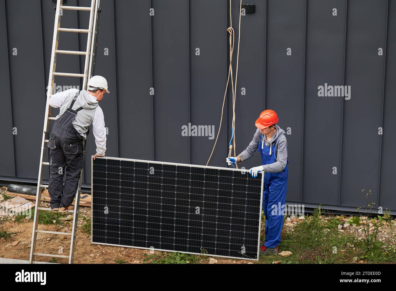 Men workers installing solar panel system on roof of house ...