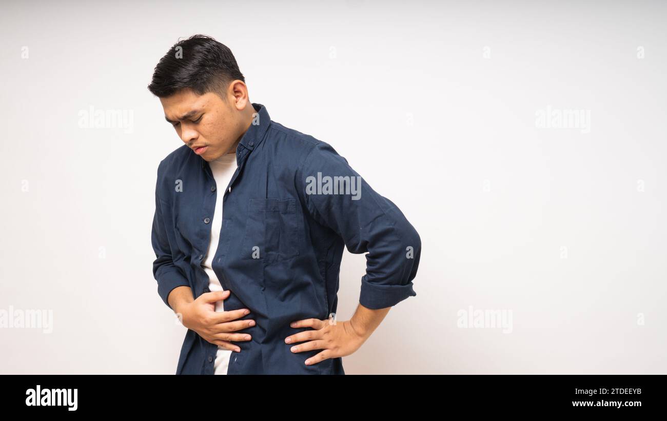 Young Asian man suffering painful stomach ache on white background Stock Photo