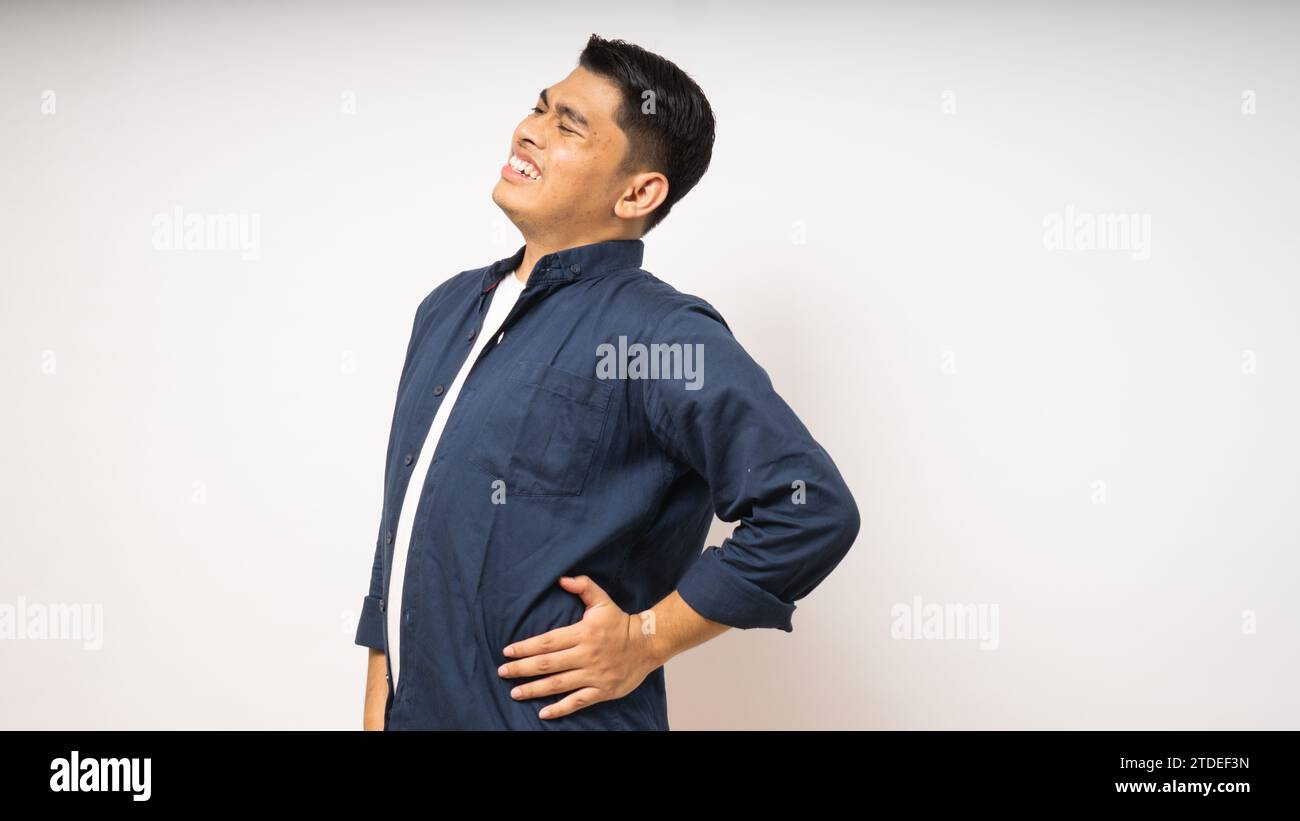 Young Asian man wearing shirt suffer low back pain on white background Stock Photo