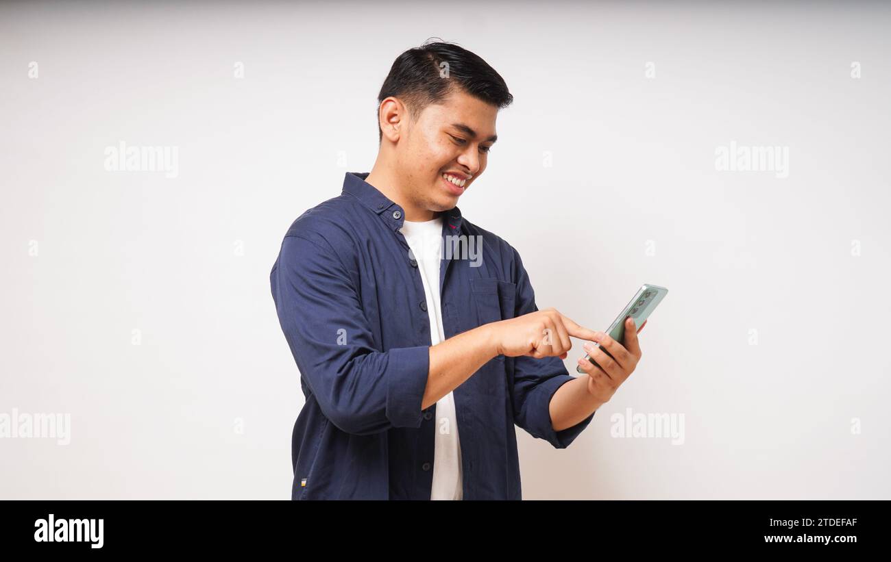 Young Asian man holding mobile phone showing enthusiastic expression Stock Photo