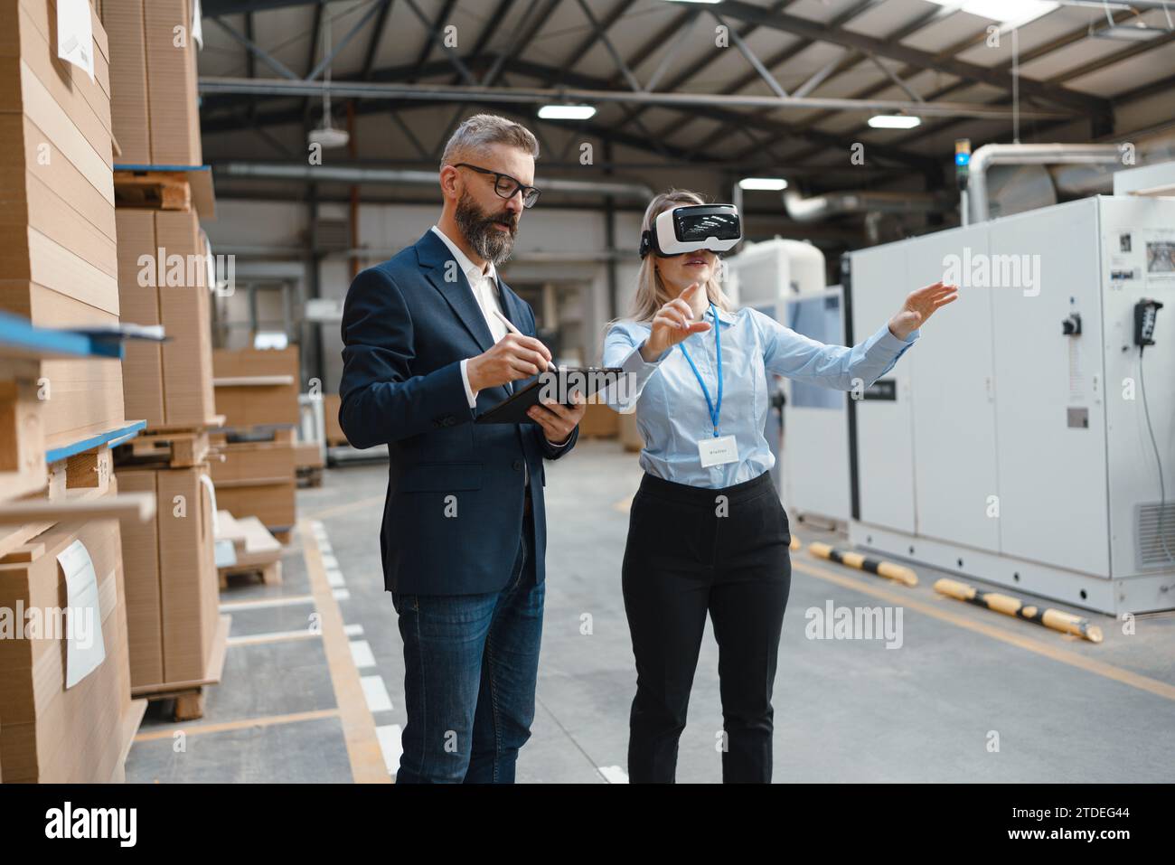 Warehouse managers talking logistics using VR, controlling stock levels ...