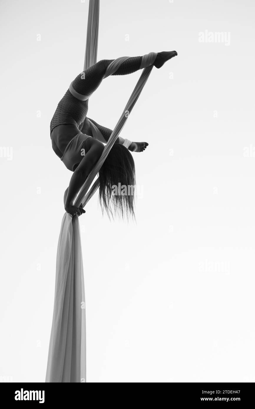 Young woman performing on aerial silk outdoors Stock Photo