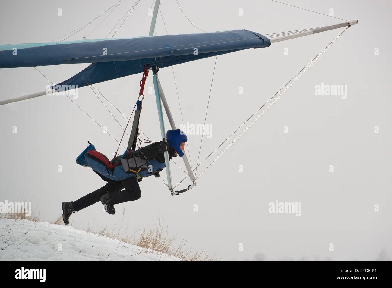 Hangglider pilot runs very fast to get airborne from the hill. Dream of flying. Modern Icarus. Stock Photo