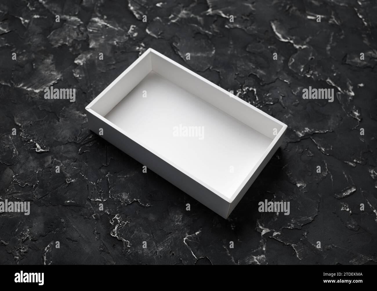 Blank white opened box on black plaster background. Stock Photo
