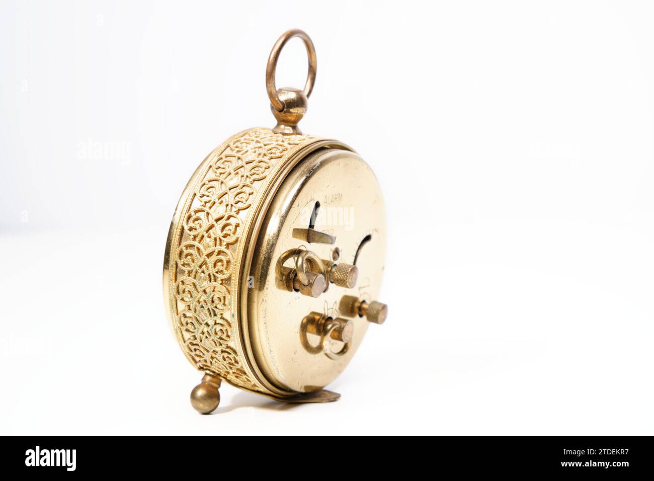 an old golden analog alarm clock with mechanical movement isolated on a