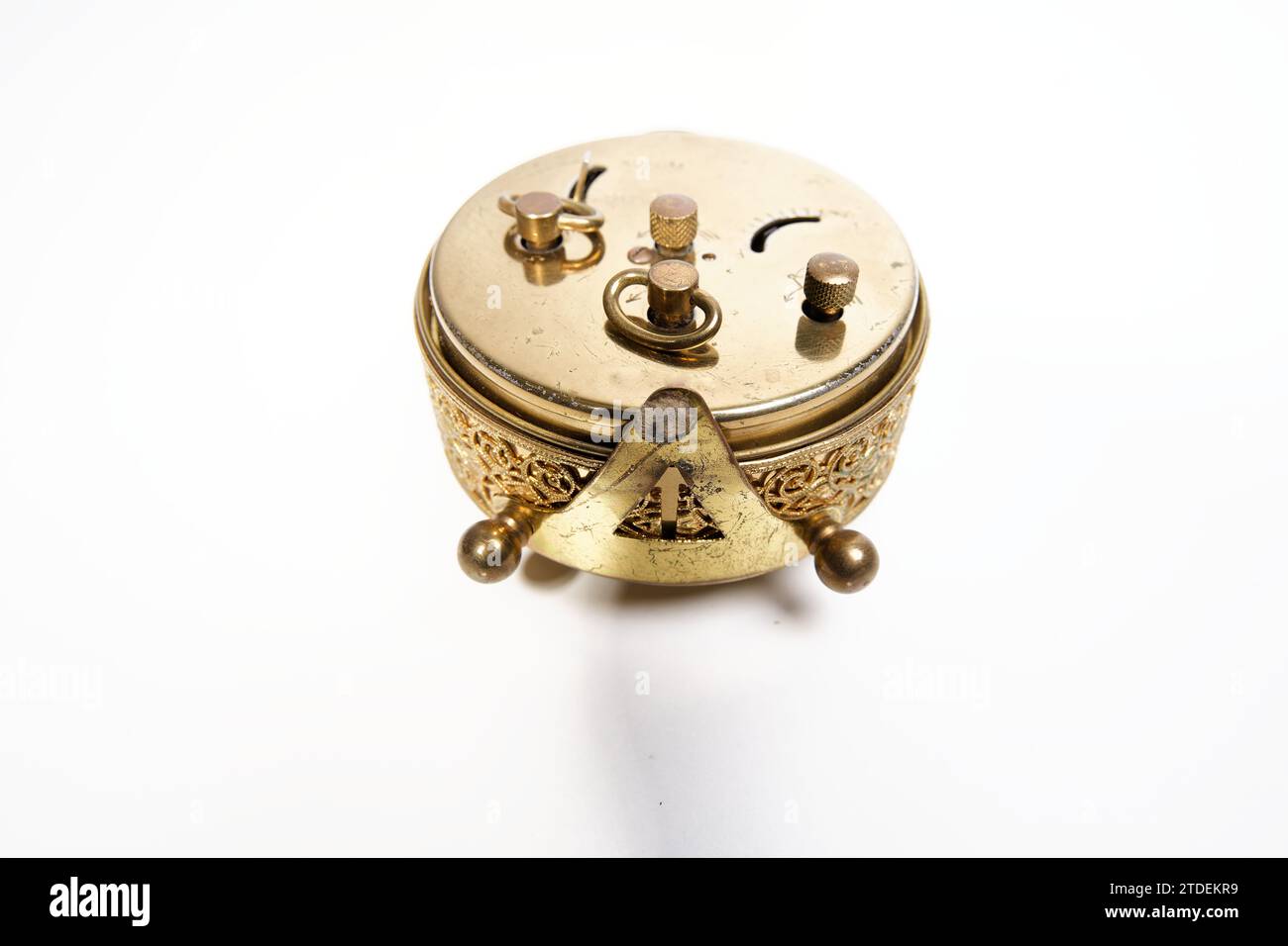 an old golden analog alarm clock with mechanical movement isolated on a