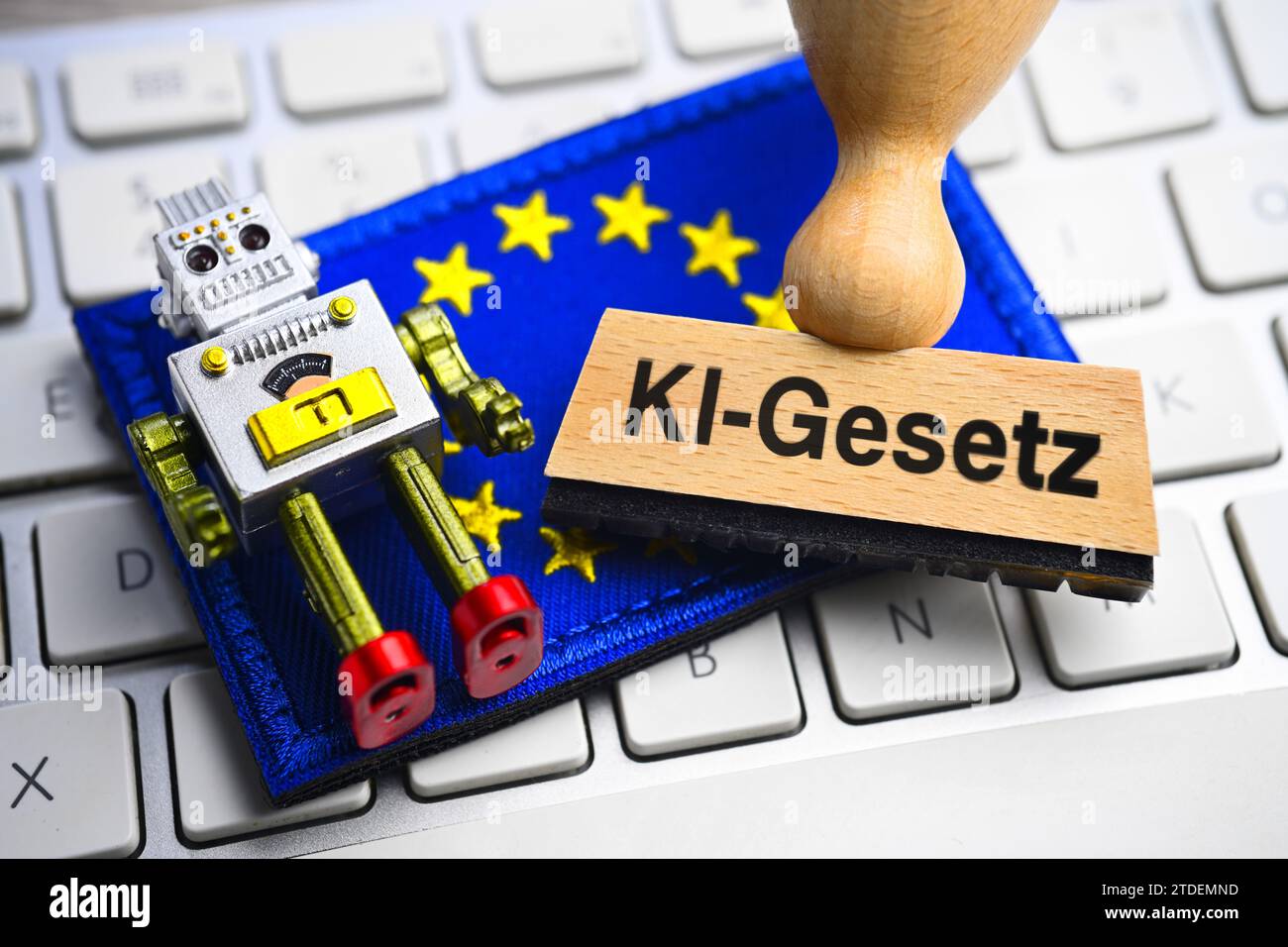 Miniature Robots And Stamps Marked AI Law On A Computer Keyboard In Front Of A European Flag, Photomontage Stock Photo
