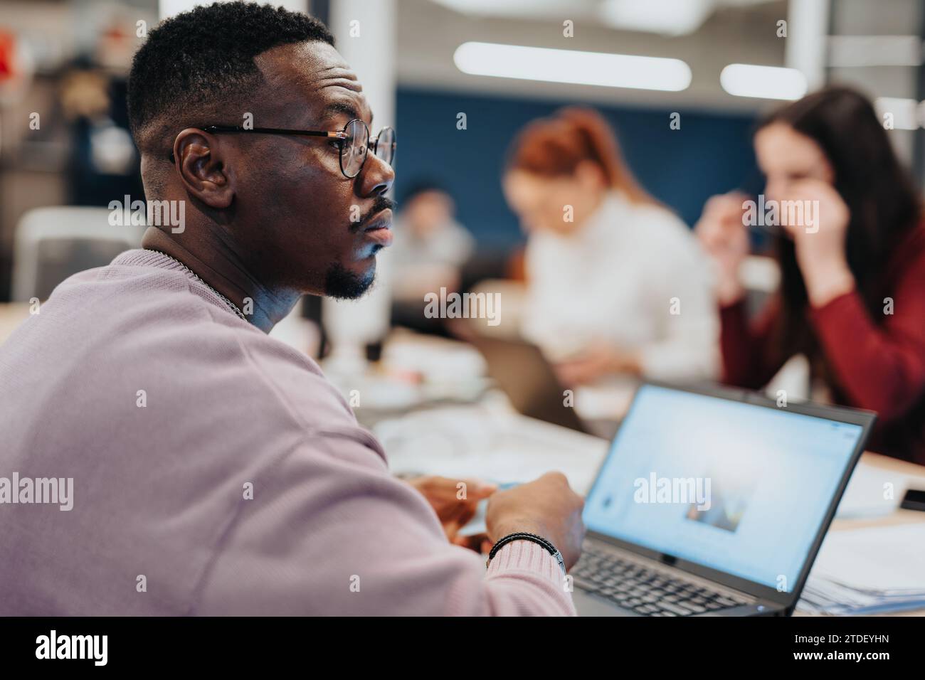 Colleagues in a corporate office working together on data analysis and market research using laptops, promoting teamwork and collaboration. Stock Photo