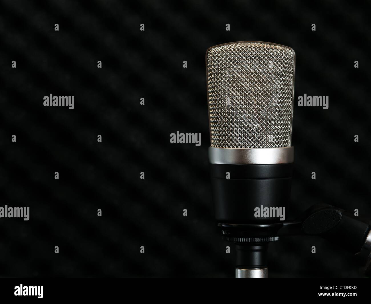 Condenser microphone with a large diaphragm on a dark background of the soundproof surface of the studio wall Stock Photo