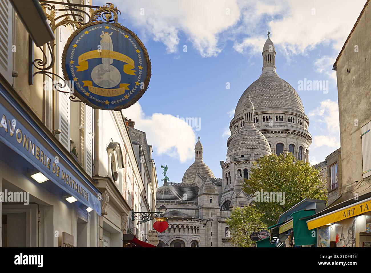 View between shops along Rue du Chevalier de la Barre looking toward the domes of Sacre Coeur Basilica, Montmartre, Paris, France Stock Photo