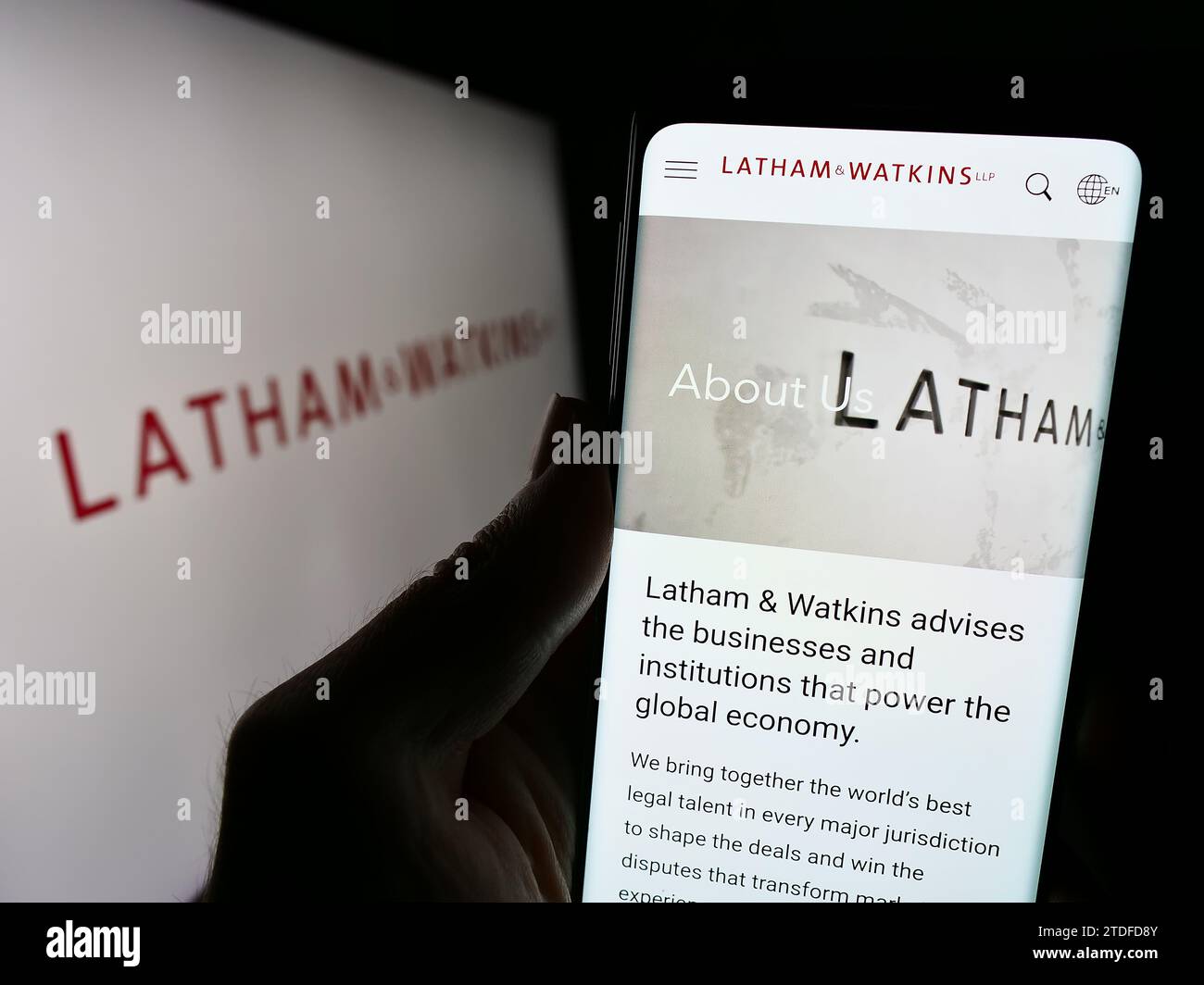 Person holding cellphone with webpage of US law firm Latham and Watkins LLP (LW) in front of business logo. Focus on center of phone display. Stock Photo