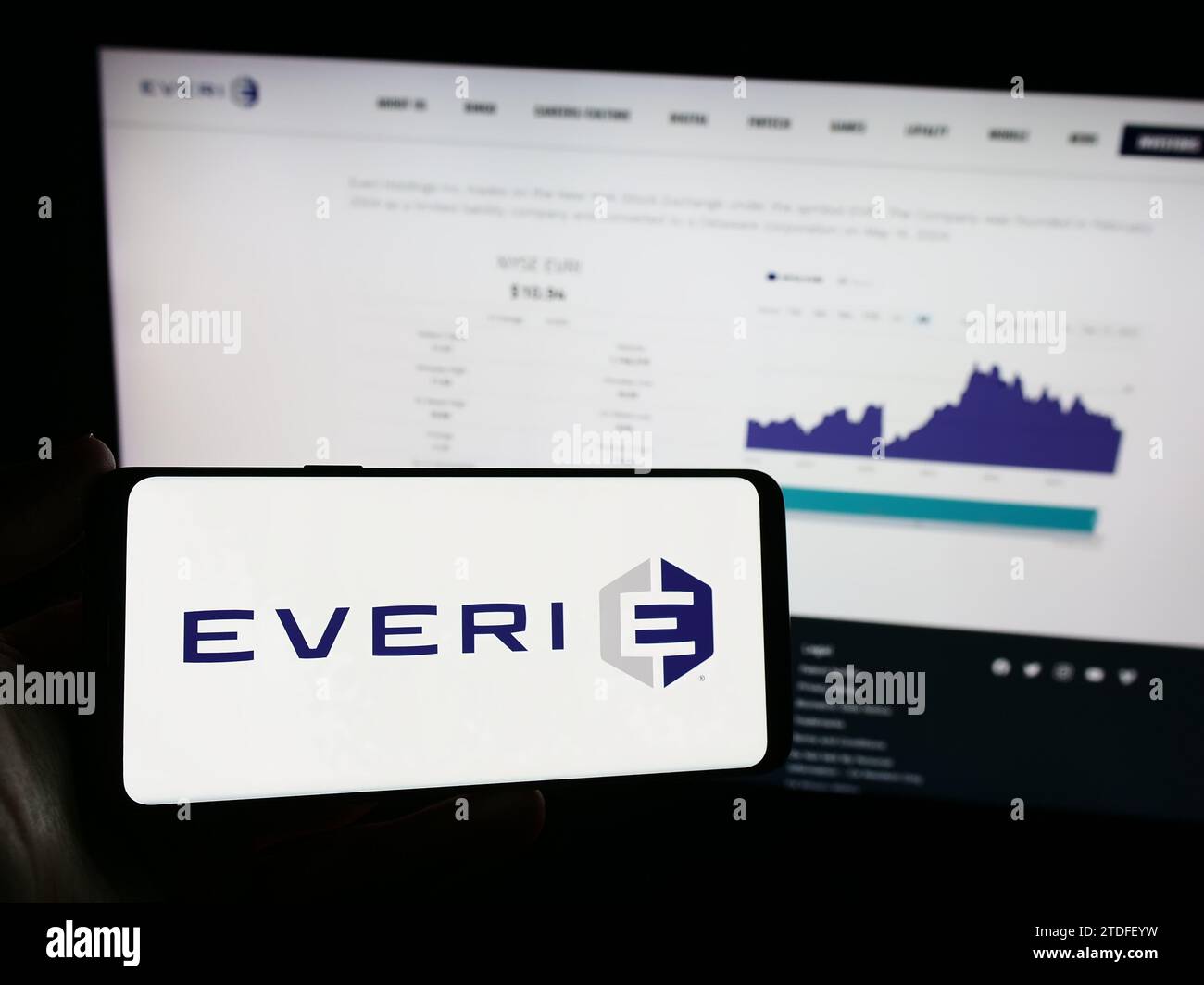 Person holding mobile phone with logo of American slot machine company Everi Holdings Inc. in front of business web page. Focus on phone display. Stock Photo