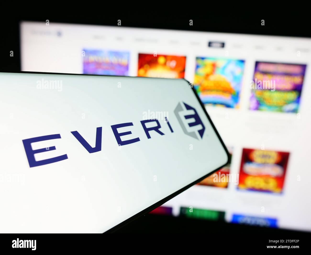 Mobile phone with logo of American slot machine company Everi Holdings Inc. in front of business website. Focus on center-left of phone display. Stock Photo