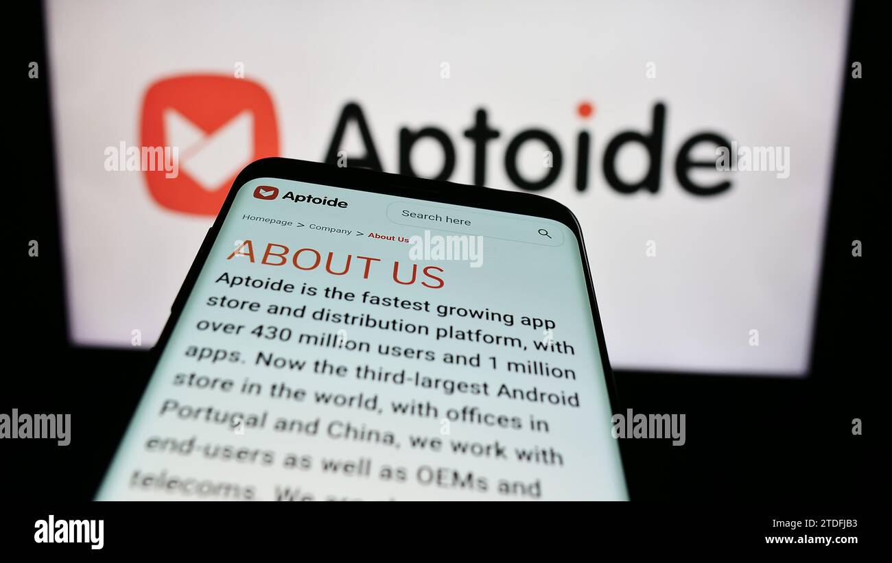 Smartphone with website of Portuguese app marketplace company Aptoide SA in front of business logo. Focus on top-left of phone display. Stock Photo