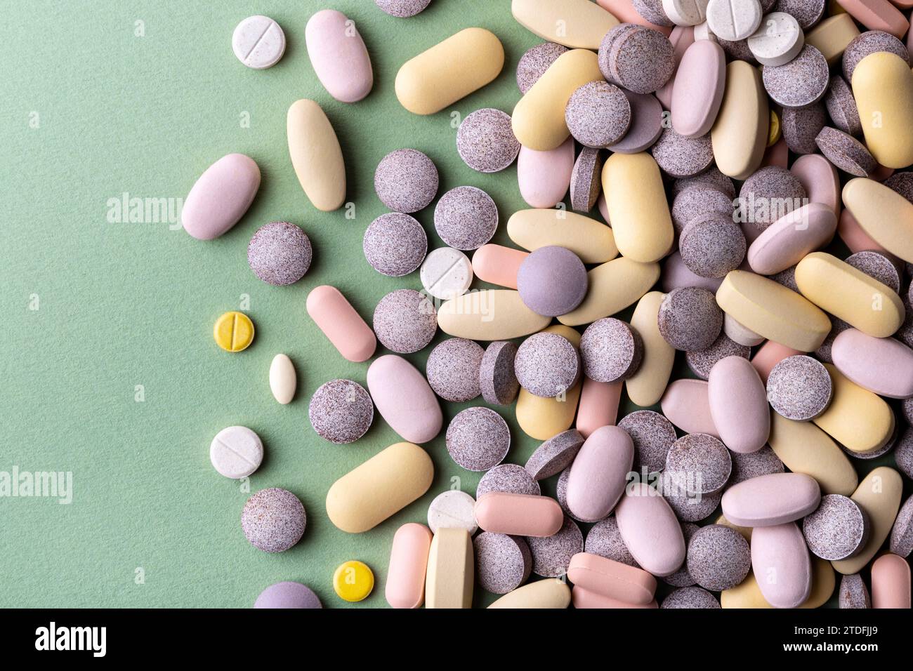 Pastel coloured pills and tablets on green background Stock Photo