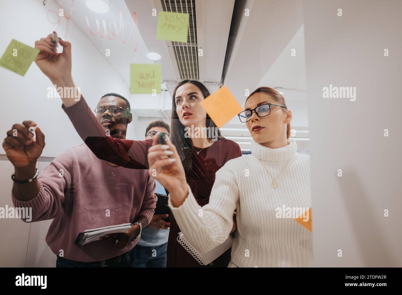 Multiracial colleagues collaborating in a glass boardroom, creating ...