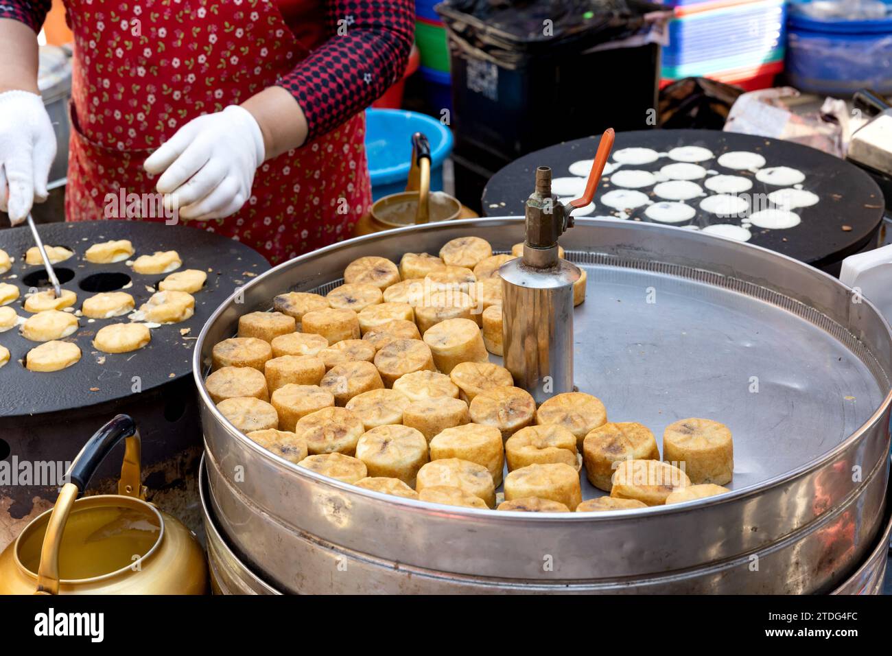 Chrysanthemum bread for sale and the hands of a merchant baking it at a traditional market in Korea Stock Photo